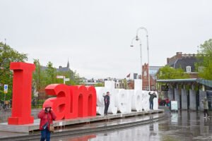 Toeristen poseren in de regen voor I am Amsterdam