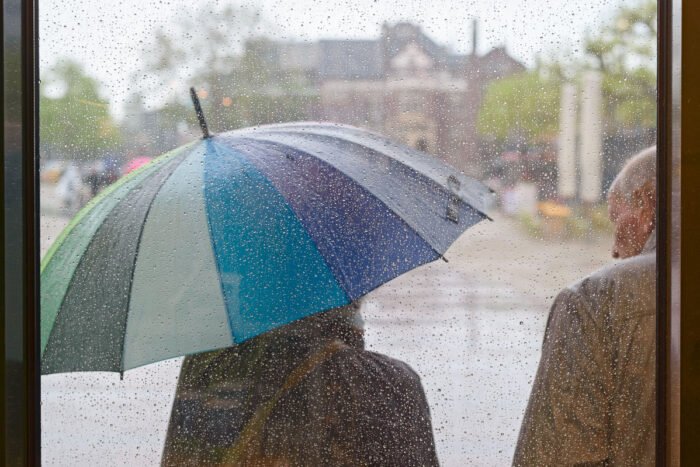 Regen in Amsterdam: schuilen onder een paraplu
