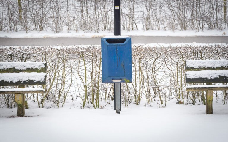Symmetrie van bankjes met prullenbak in de winter sneeuw